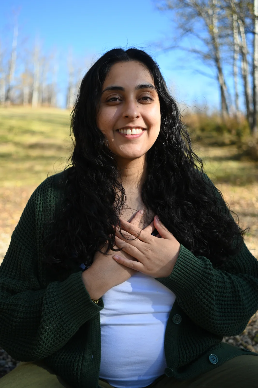 Kacy smiling outdoors with her hands over her heart.